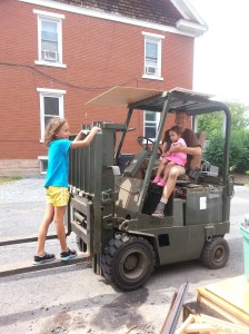 Tanya and Leena with a gleeful Papa on the forklift